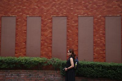 Woman standing against brick wall