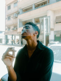 Young man while sitting in car and smokes a cigarette with the effect of a vintage old film camera 