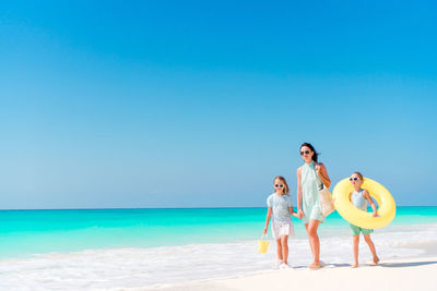 Mother and daughters walking on beach