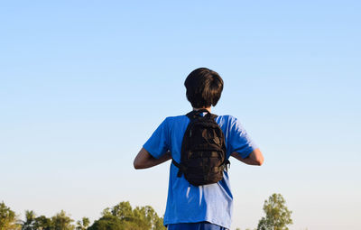 Rear view of man standing against clear blue sky