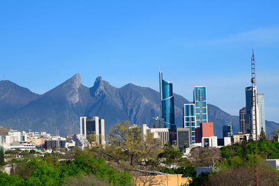 Buildings in city against clear blue sky