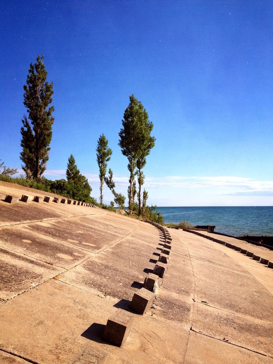 sea, blue, beach, horizon over water, tranquil scene, water, tranquility, sand, the way forward, scenics, clear sky, sky, nature, tree, shore, beauty in nature, copy space, road, sunlight, coastline