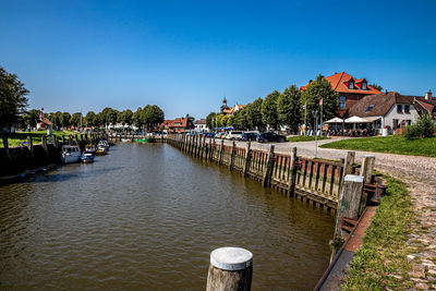 River amidst houses and buildings against clear blue sky