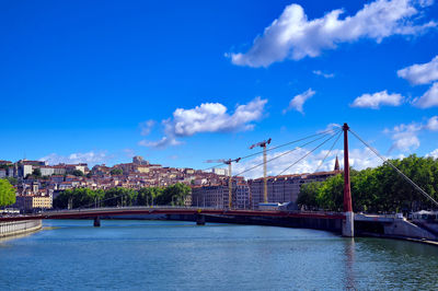 Bridge over river in city against blue sky