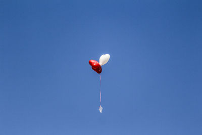 Three heart shape balloons in air against clear sky