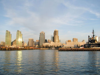 City at waterfront against cloudy sky