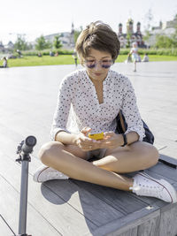 Woman in public park.  female is texting on smartphone after riding kick scooter, urban transport.