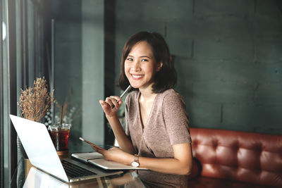 Portrait of smiling young businesswoman using laptop while sitting on table