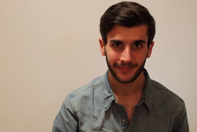 Portrait of young man standing by wall