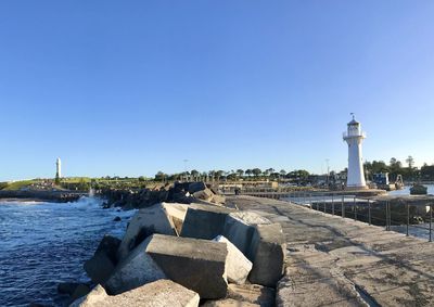 Lighthouse on beach against buildings