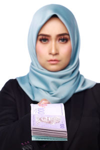 Portrait of woman holding paper currency while standing white background