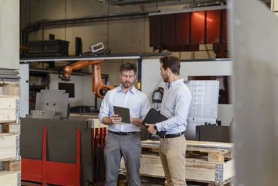 Businessmen having discussion while using digital tablet at factory