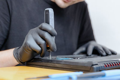 A man unscrews a bolt on a laptop with a screwdriver.