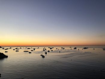 Boats in sea at sunset