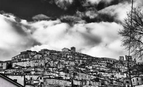Low angle view of buildings against cloudy sky in village