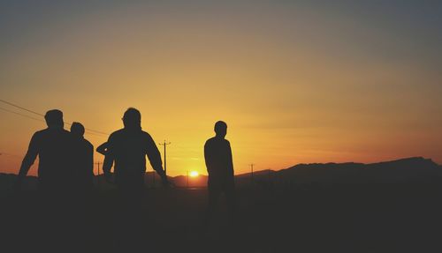 Silhouette friends against orange sky