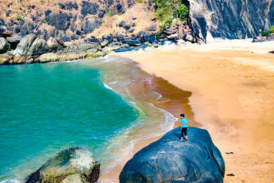 High angle view of boy on rock in sea