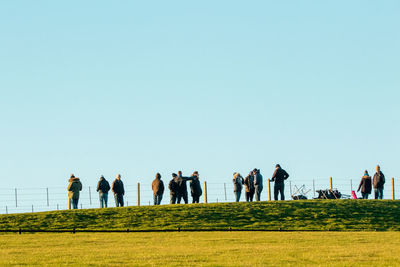 Group of people on field against clear sky