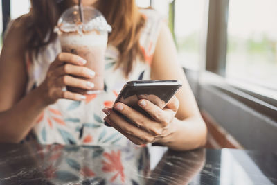 Midsection of woman holding smart phone