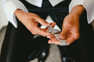 Low section of man holding wristwatch