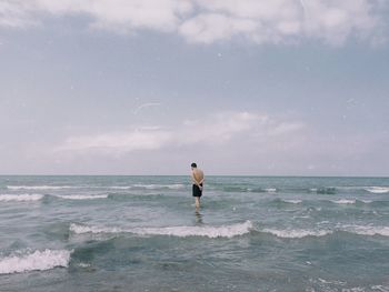 Rear view of man on beach against sky