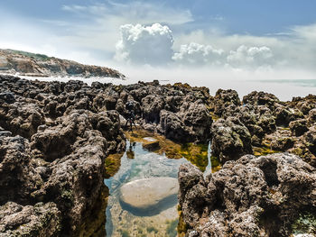 Scenic view of rocks in sea against sky