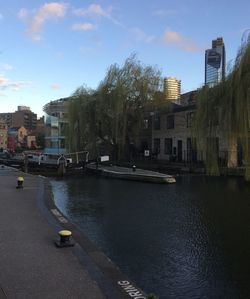 Buildings by river against sky in city