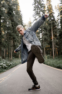 Portrait of man standing on road in forest