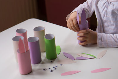 A little child making easter bunny gift on white table background. child holding paper easter rabbit