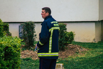 Side view of young man standing against wall