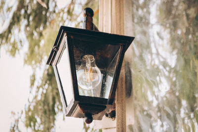 Close-up of illuminated lamp on table against trees