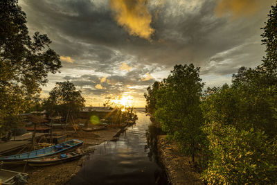 Boats moored in canal against sky during sunset