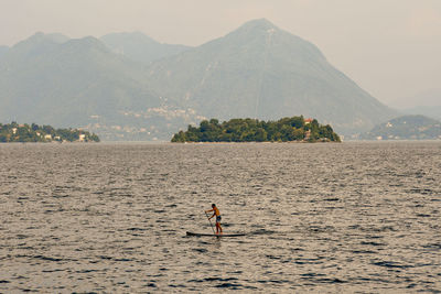 Man by sea against mountains against sky