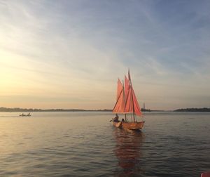 Sailboat sailing on sea against sky during sunset