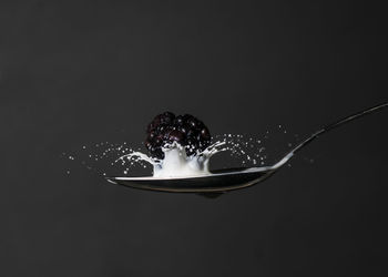 Close-up of water splashing on glass against black background