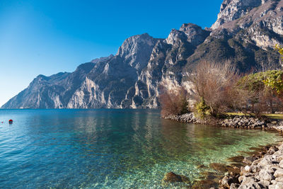 Scenic view of sea and mountains against clear blue sky