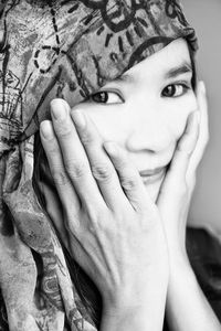 Close-up portrait of young woman with hands on cheek