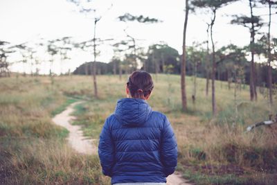 Rear view of woman walking on trail at woodland