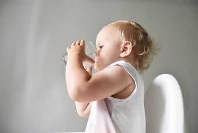 Cute baby girl standing against white background