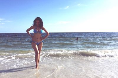 Full length of woman in bikini walking on shore against sky