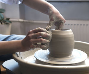 A potter works on a fast spinning potter's wheel and makes a vase with wet sponge.