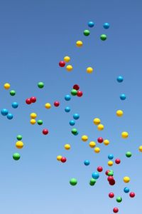 Low angle view of multicolor balloons flying against blue sky