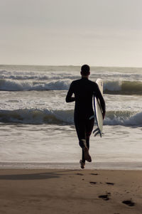 Rear view of man on beach against sky