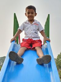 Young boy sitting on top of a baby slide. cute smiling 5 years teen boy portrait