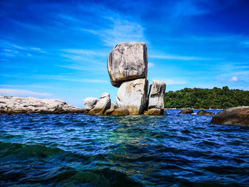 Rock formation in sea against blue sky