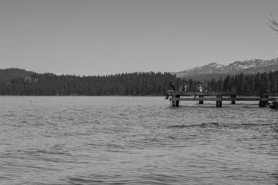 People on lake against clear sky