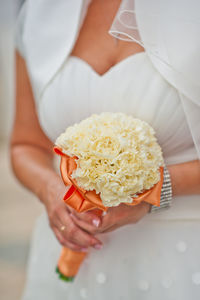 Midsection of bride holding carnation bouquet