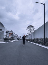 Man on street amidst buildings against sky