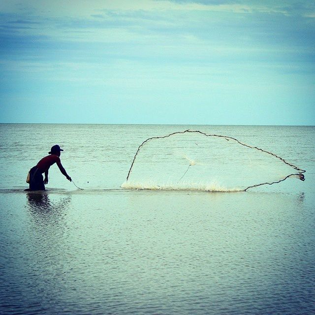 water, sea, horizon over water, leisure activity, lifestyles, full length, sky, waterfront, men, tranquility, holding, nature, scenics, beauty in nature, tranquil scene, fishing, vacations, silhouette