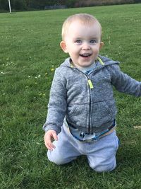 Portrait of smiling boy kneeling on lawn in city